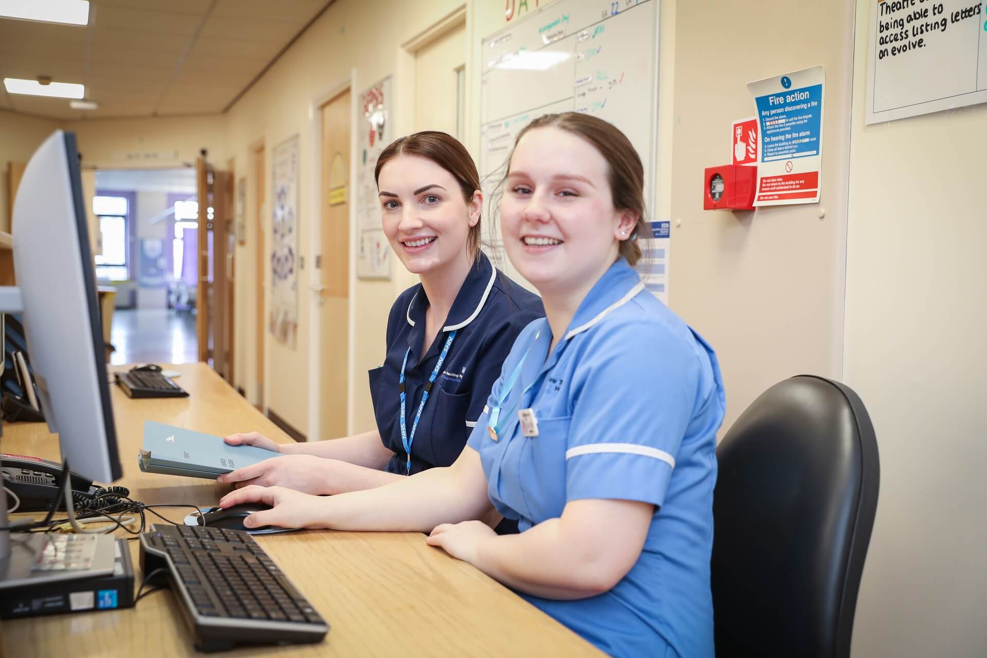 Smiling female staff members sitting behind reception desk