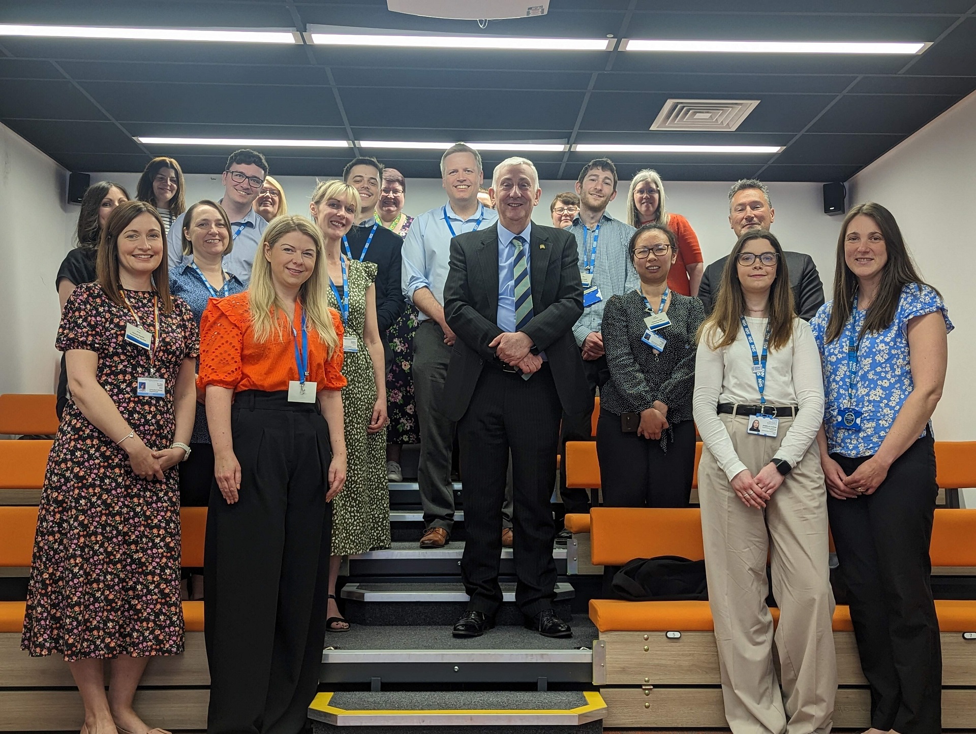 Sir Lindsay Hoyle in a group photo with a dozen or so Lancashire Teaching Hospitals employees, one of whom is Kevin McGee. They are all standing together, smiling, looking very professional.