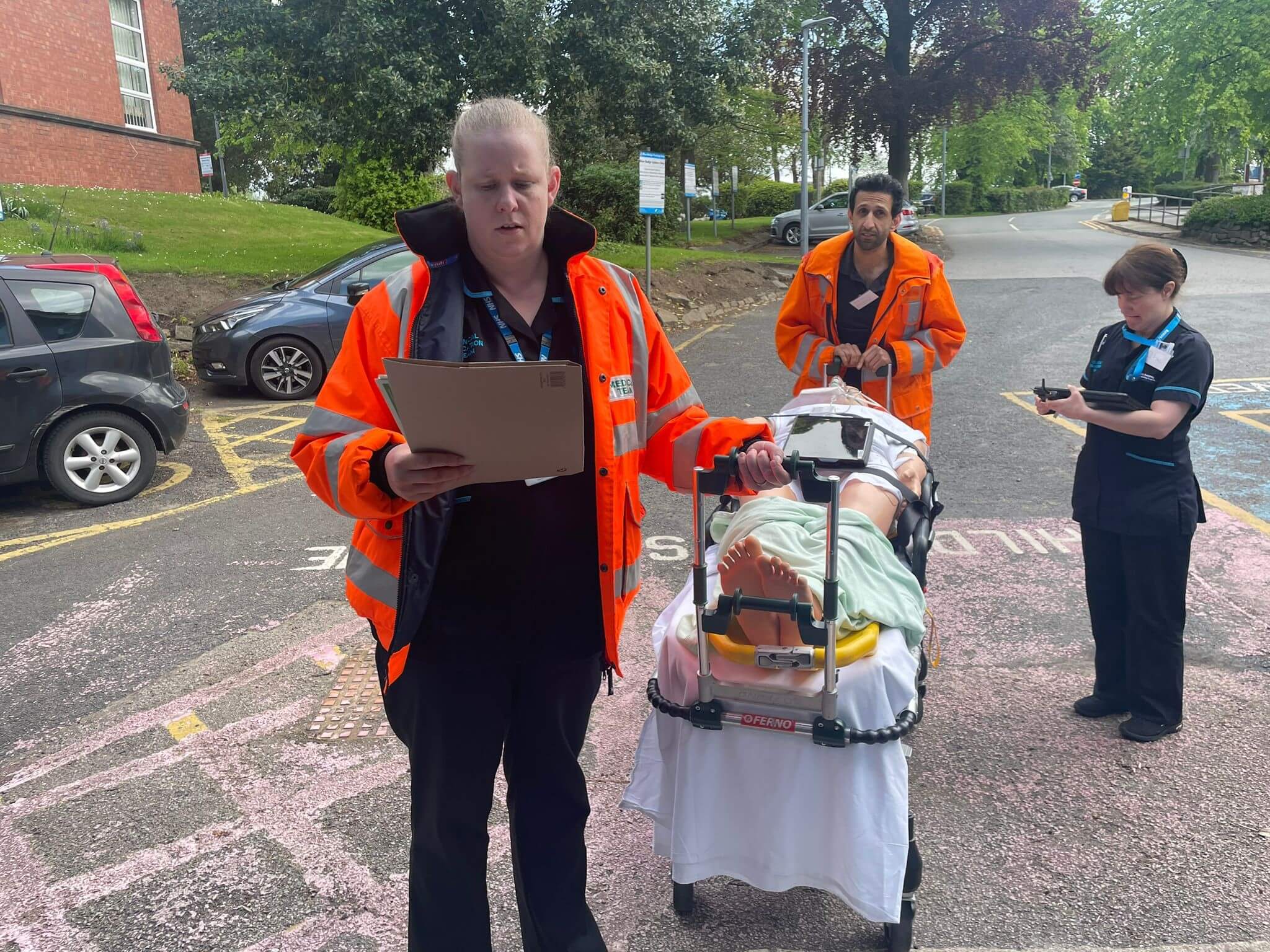 3 NHS staff member preparing to push a mannequin on a mobile patient bed