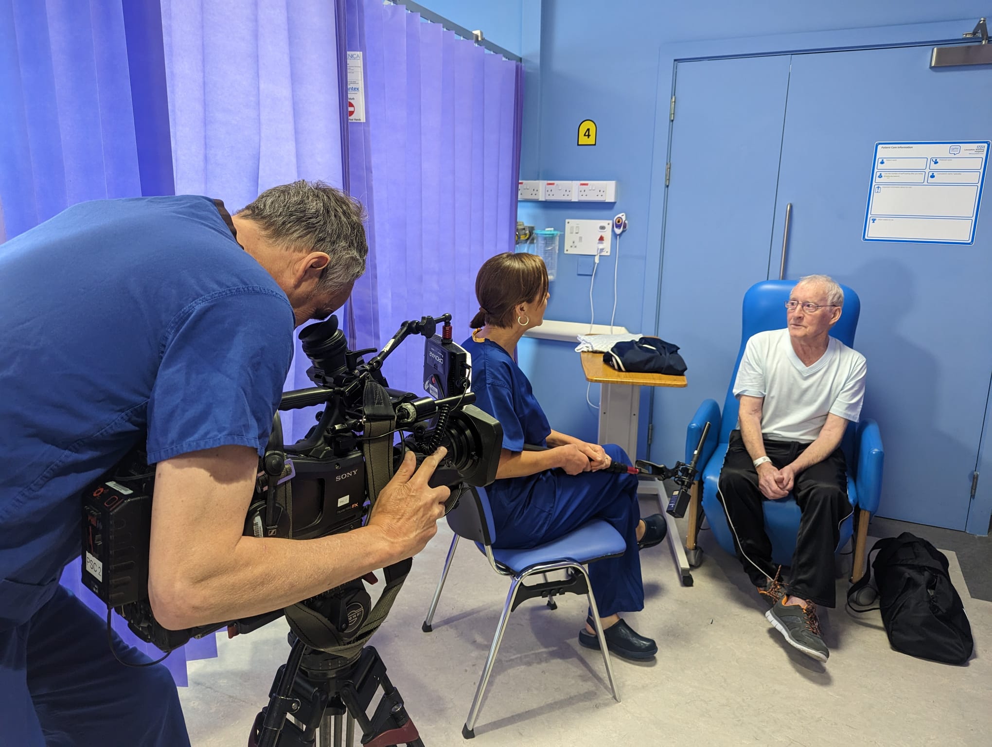 One person being interviewed. Interviewer sitting on a chair facing them. Cameraman behind.