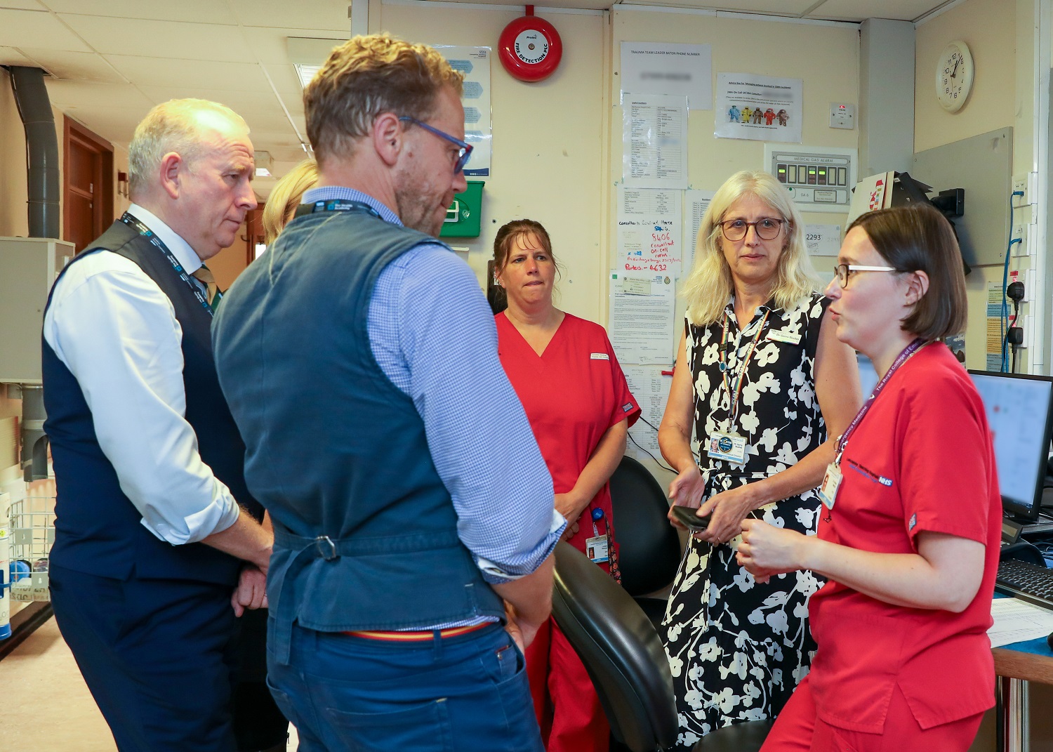 Lord Markham speaking with a a female staff member dressed in a red medical uniform