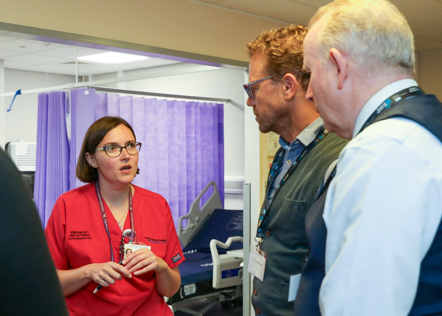 Lord Markham talks to a female staff member dressed in a red medical uniform