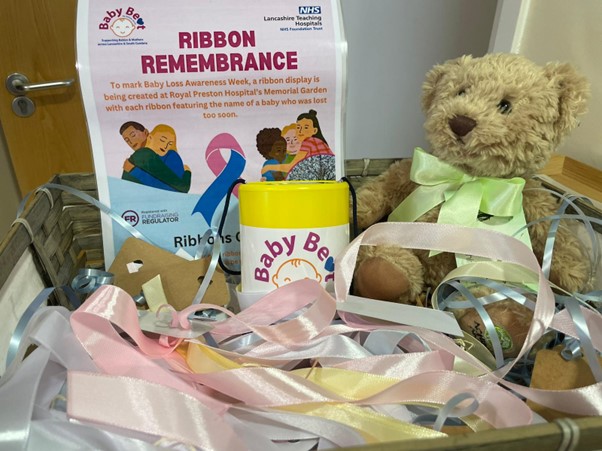 Photo of Ribbon Remembrance poster, a teddy bear and a donation pot for coins
