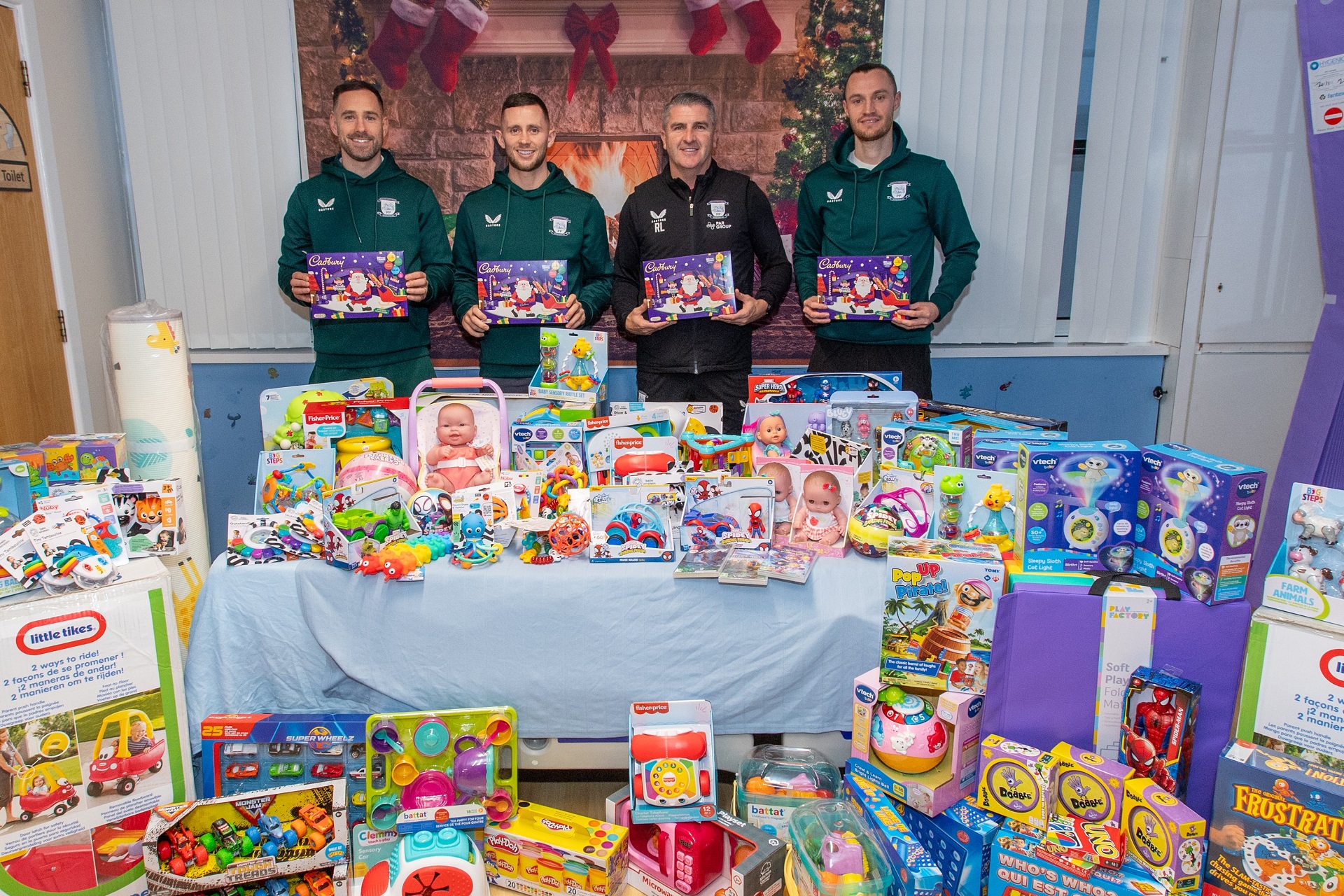 PNE  footballers standing behind a table full of toys and gifts