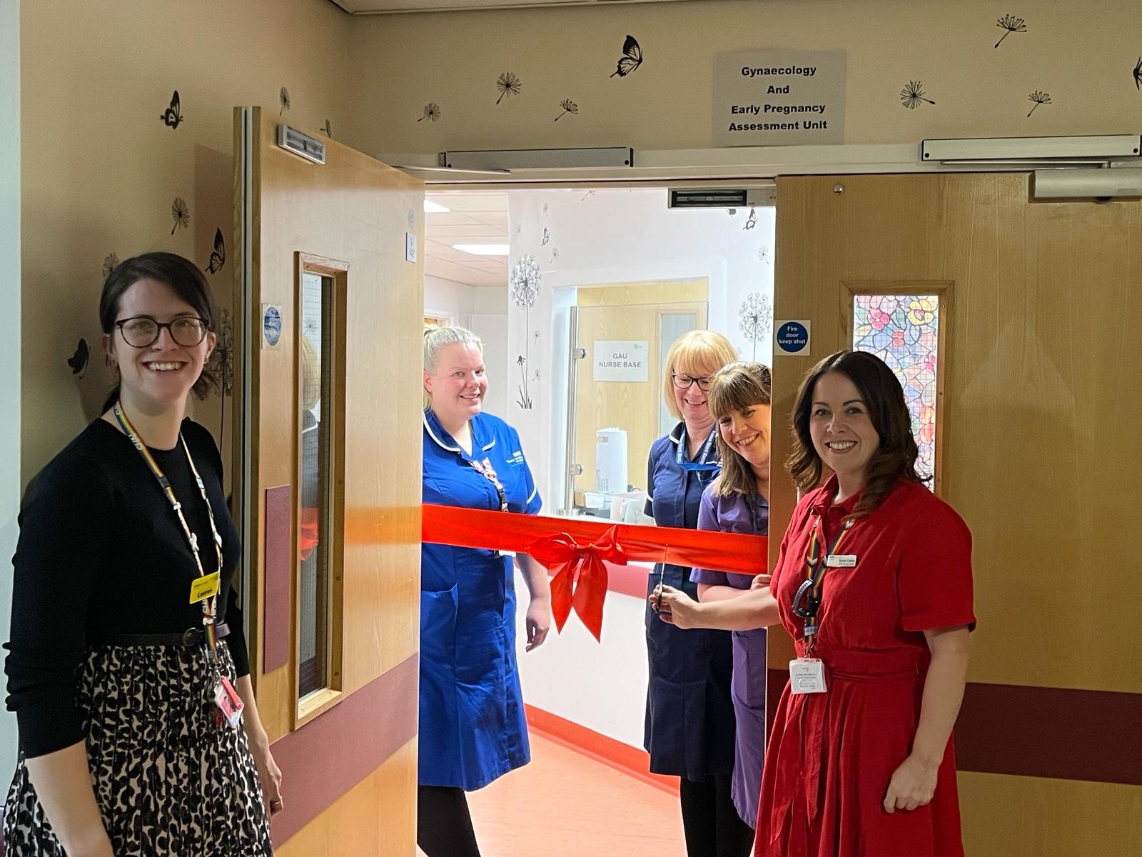 Staff members cutting red ribbon in front of entrance