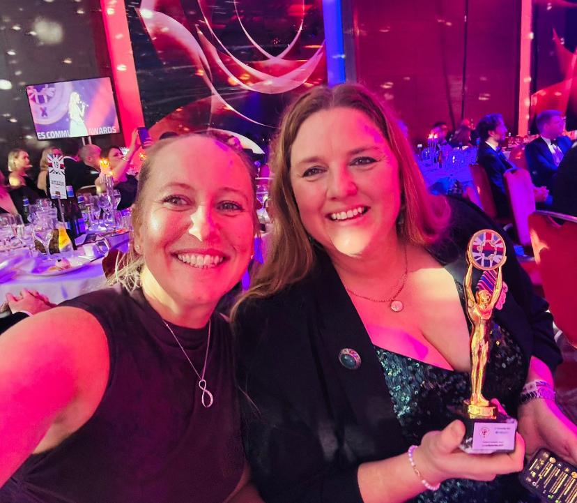 Lt Col Rachel Diss holding her award, smiling with another woman next to her