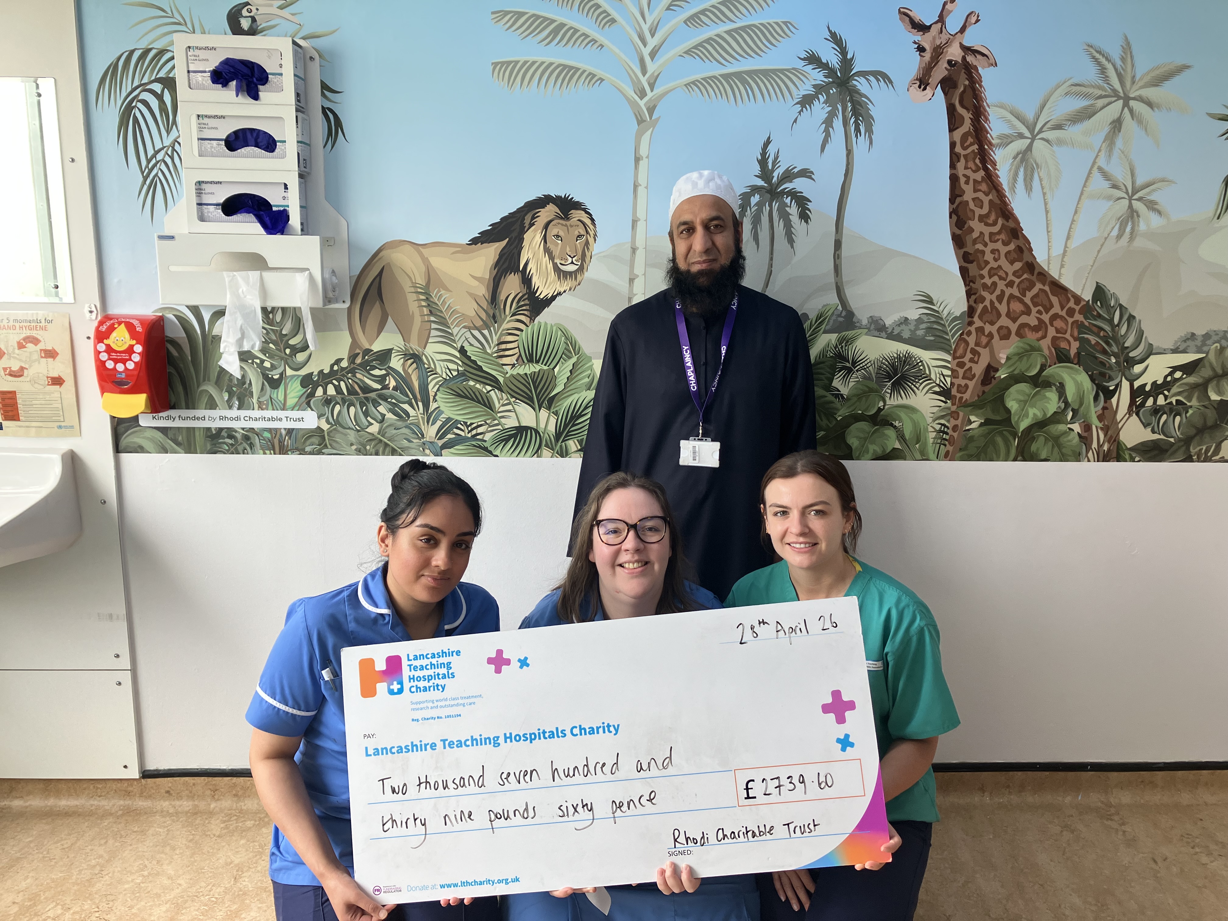 Staff members at the children's emergency department holding a big charity cheque and smiling