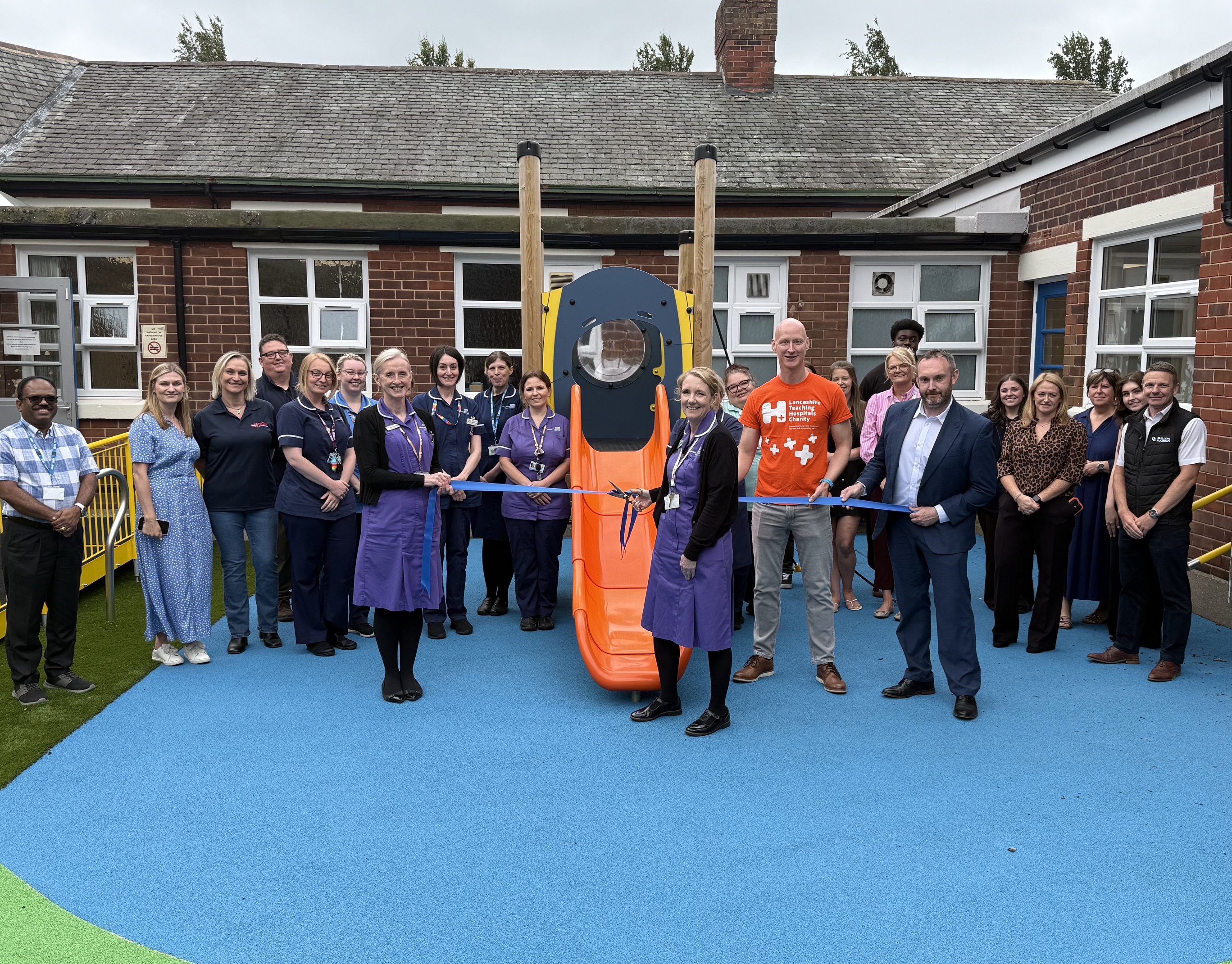 Group photo of NHS and school staff at playground official ribbon cutting
