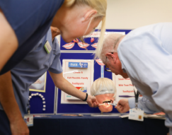 a dental hygiene dummy head being looked at by two people