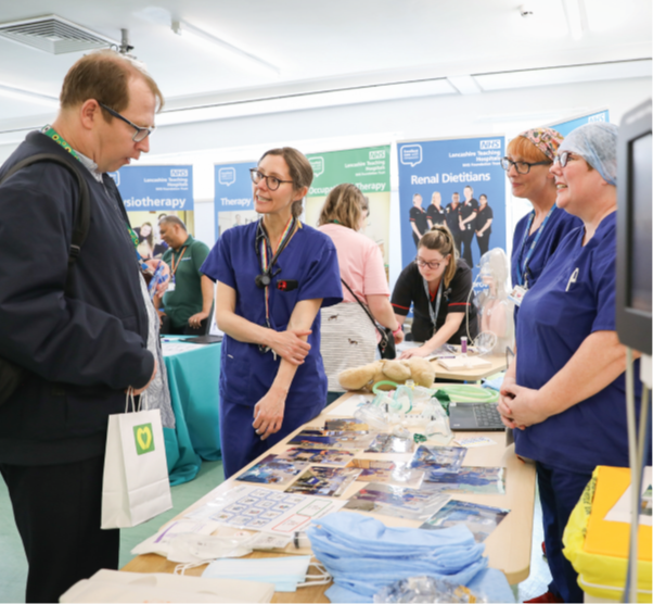 People attending stands at an event with hospital staff