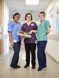 3 members of staff looking at files in a corridor