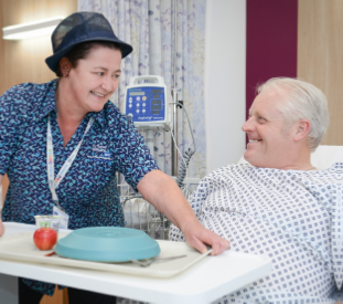 member of staff with a patient in a hospital bed