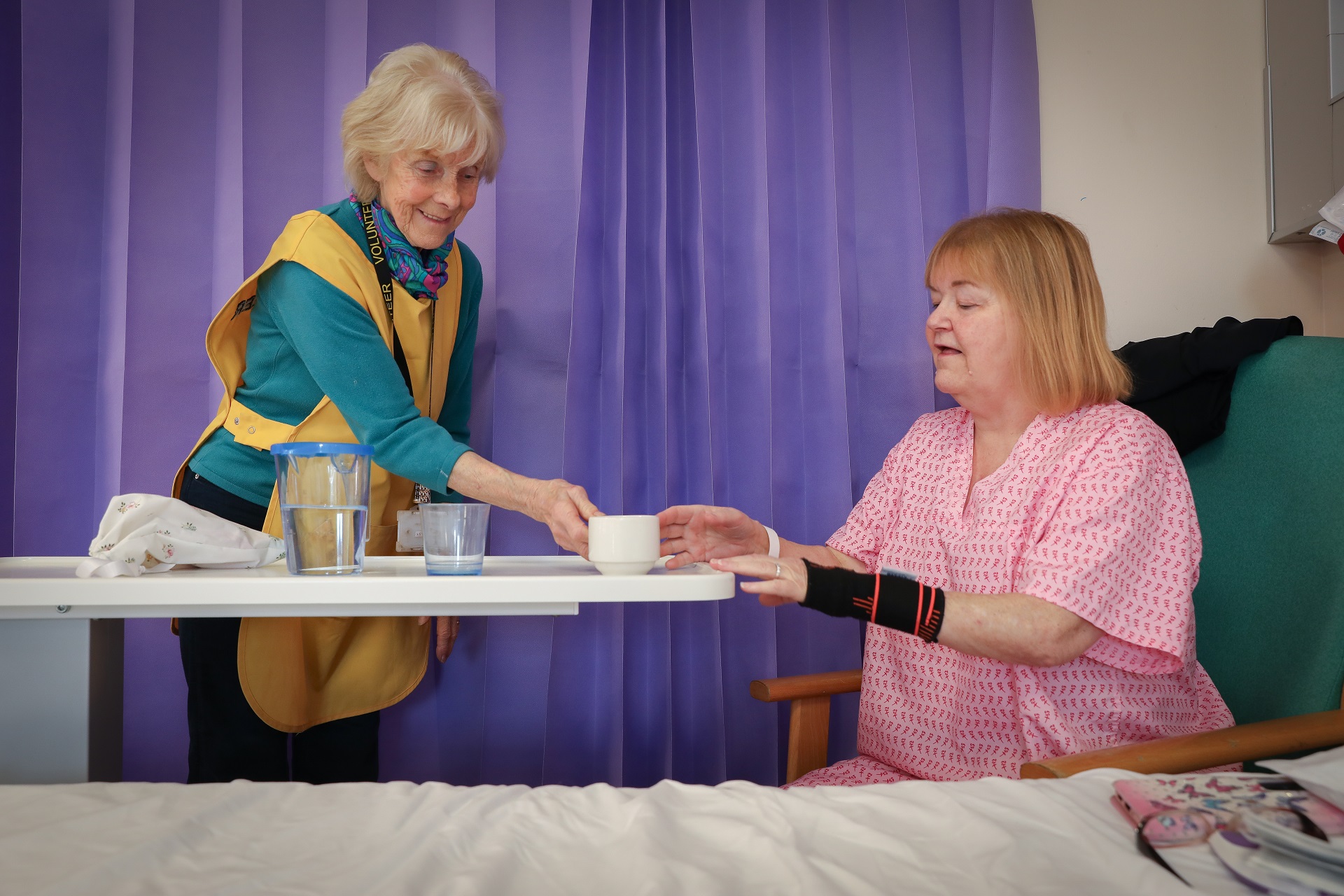 Photo of a volunteer serving a brew to a patient