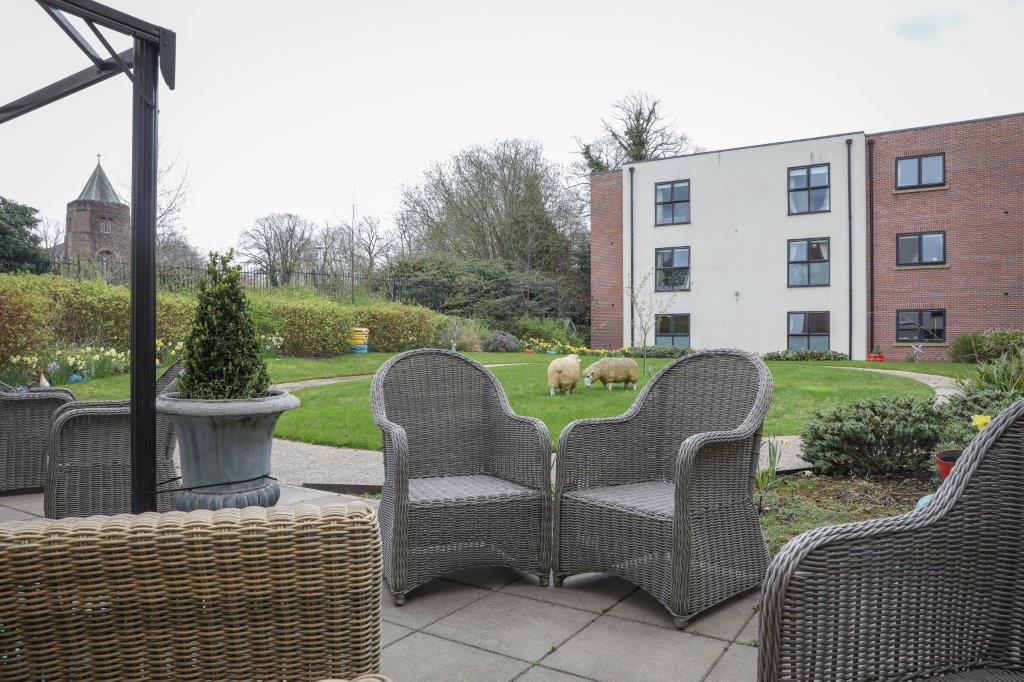 Photo of coffee tables and chairs on an outside premises of Finney House, overseeing a beautiful, green lawn with sheep statues