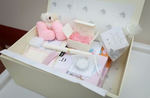 A photo of a white box showing plushies, cards and other nice items