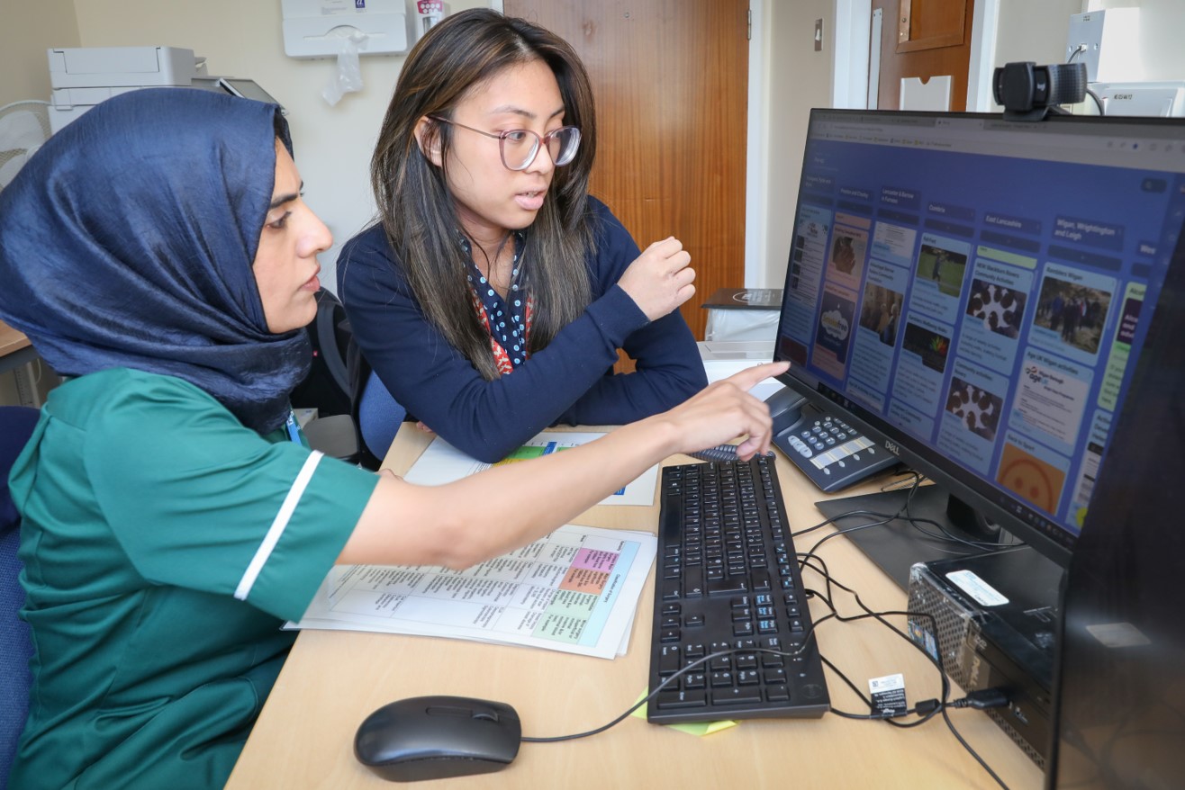 A photo depicting two female NHS professionals looking at a computer monitor